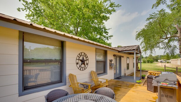 A covered patio with outdoor seating, a grill, and a large window with a view. - Emory Vacation Rental w/ Lake Fork Boat Access! (Emory)