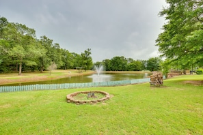 Escape to a serene park setting surrounded by lush greenery and a tranquil pond with a central fountain.