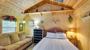 Une pièce chaleureuse avec un plafond en bois, un lit recouvert d’une courtepointe blanche, une commode en bois et une fenêtre avec des stores.