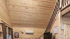Et trægulv med en sofa, et lille bord, et tæppe og en trappe, der fører op til et højere plan.