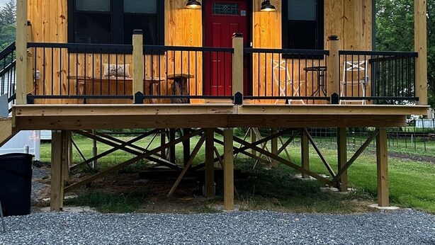 En træhytte med rødlakeret dør, en balkon og et skilt der står 'TWO TIRE'.
