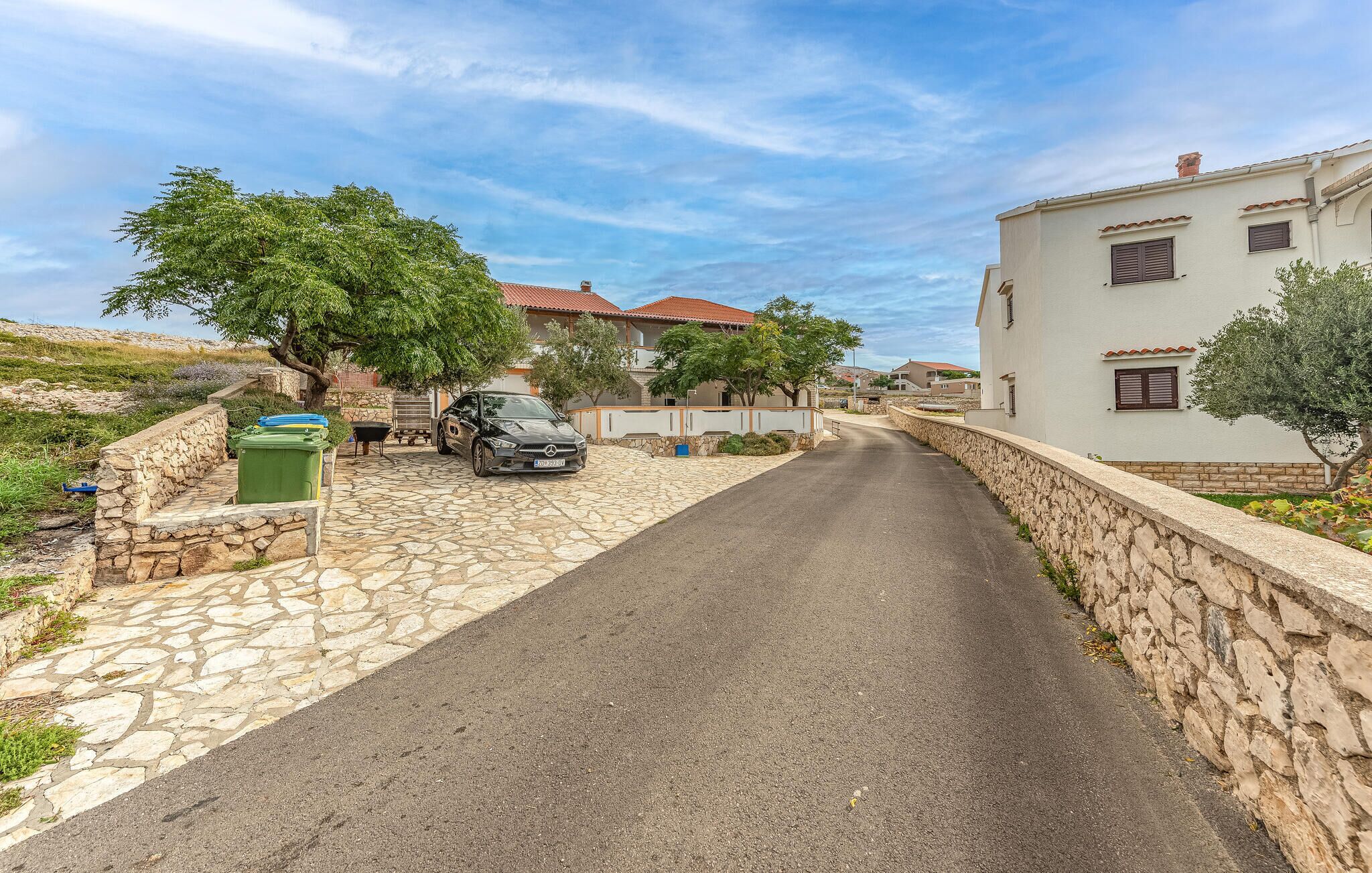 Une rue étroite bordée de murs de pierre et d’immeubles d’habitation aux toits recouverts de tuiles rouges.
