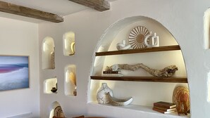 Un soggiorno con un divano marrone, una mensola a parete con oggetti decorativi e un quadro incorniciato.