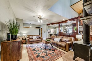 A spacious living room with a fireplace, leather sofas, a coffee table, and a large rug.