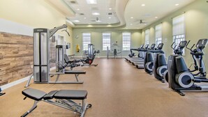 Ein Fitnessraum mit Laufbändern, Kraftgeräten und Bänken.