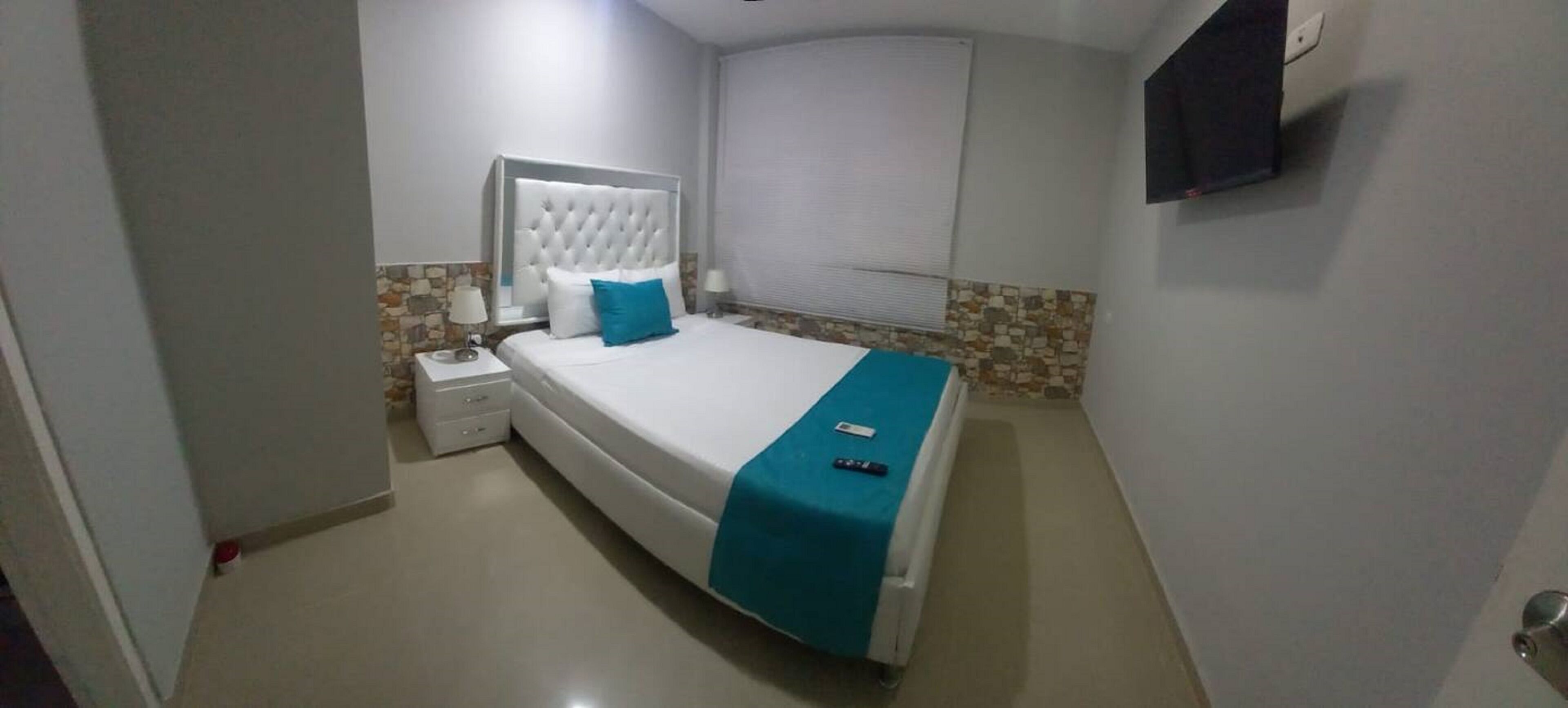 A neatly arranged bedroom with a bed, bedside table, and a TV mounted on the wall.