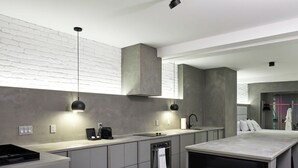 A modern kitchen with grey cabinets, a built-in oven, and a coffee maker. A large flat-screen TV displays the Netflix logo.