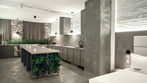 A modern kitchen with a central island, grey cabinets, and a brick accent wall.