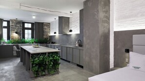 A modern kitchen with a central island, grey cabinetry, and a hanging plant. - PREMIUM LOFT | The Signature (Montréal)