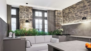 A modern kitchen with a stone wall, a built-in sofa, and a dining area. - PREMIUM LOFT | The Signature (Montréal)