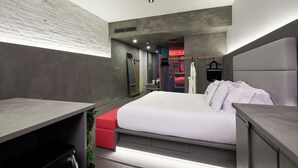 A modern bedroom with a bed, a desk, and a red bench.