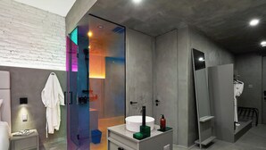 A modern bathroom with a glass shower enclosure, a white sink, and a vanity with a mirror.