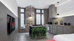 A modern kitchen with a stone accent wall, a built-in island with greenery, and a red bench.