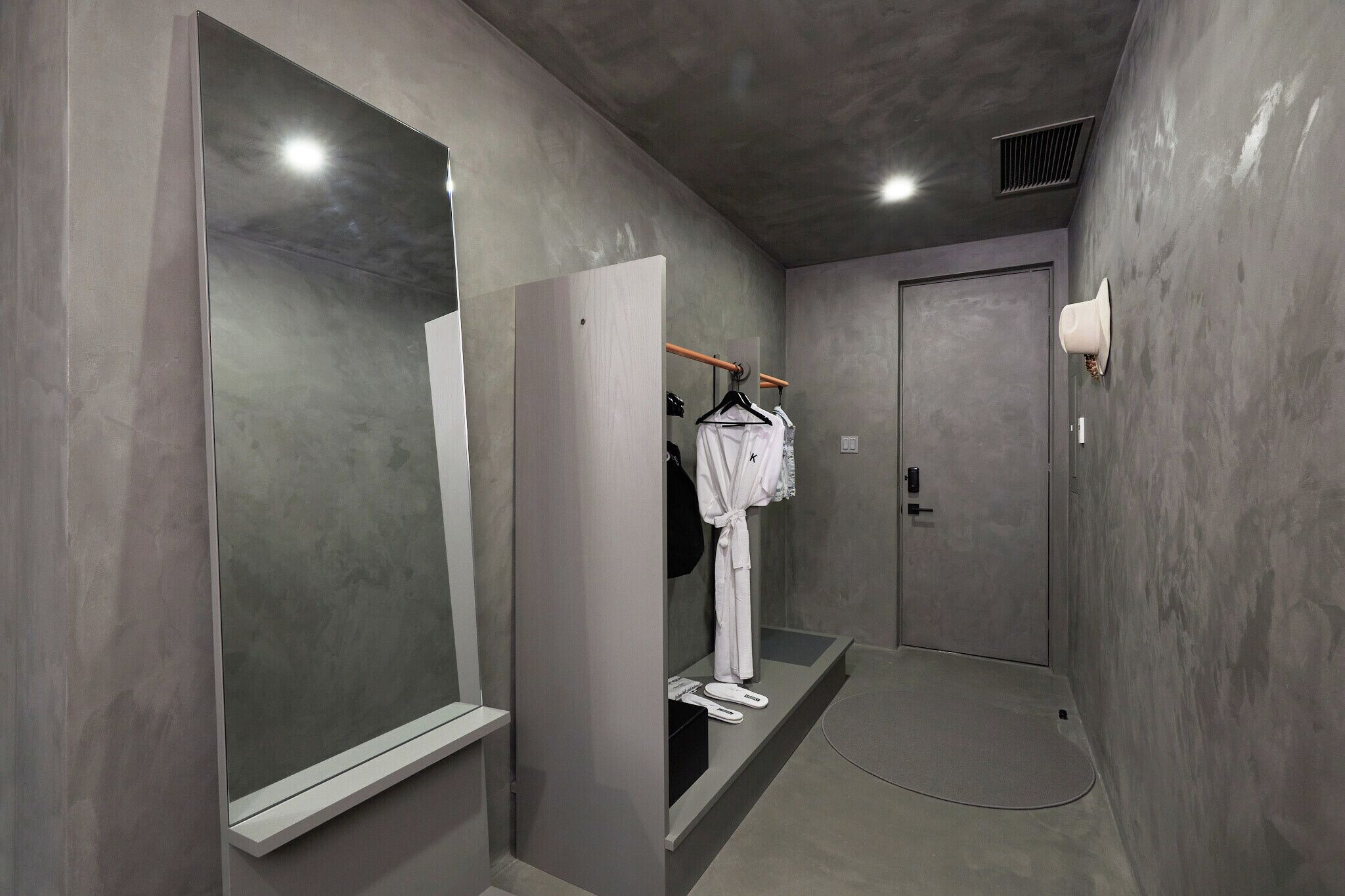 A modern bathroom with a large mirror, a robe hanging on a rack, and a shower area.