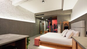A modern hotel room with a large bed, a desk, and a small seating area.