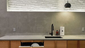 A modern kitchen with a white brick backsplash, a black faucet, and a dish drying rack. - LOFT | The Wood Mood (Montréal)