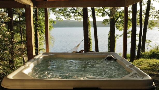 A hot tub with a view of a lake surrounded by trees. - Seneca Lake Waterfront Cottage with Hot Tub on FLX Wine Trail (Burdett)