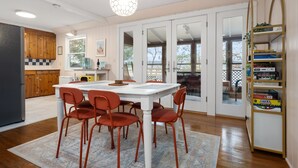 A modern kitchen with a white table and red chairs, wooden cabinets, and a view of the outdoors. - Seneca Lake Waterfront Cottage with Hot Tub on FLX Wine Trail (Burdett)