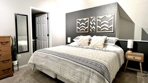 Une chambre à coucher comprenant un lit, une commode, un miroir et des œuvres d’art murales.