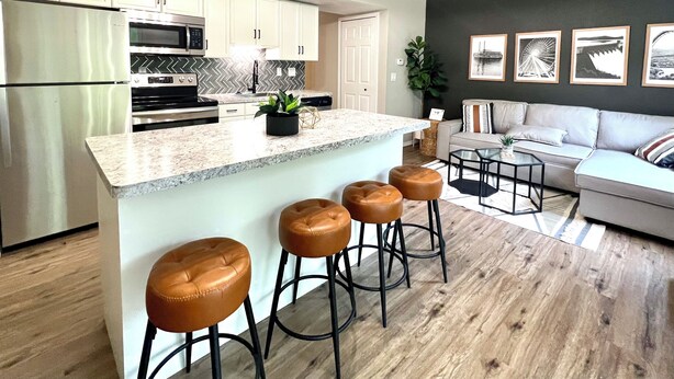 Une cuisine moderne dotée d’un îlot central, de tabourets de bar et d’un coin repas comprenant un canapé et une table basse.