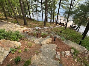 A stone staircase leading to a dock by a lake, surrounded by trees.