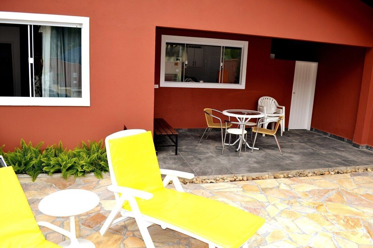 A patio area with a stone floor, yellow and white chairs, a small round table, and a window with curtains.