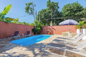 Relax by the pool surrounded by lush greenery and lounge chairs.