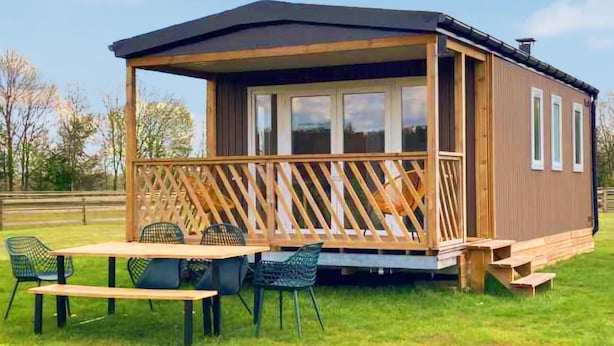 A wooden cabin with a covered porch, a table, and chairs. - Gorgeous apartment in Schoonloo (Schoonloo)