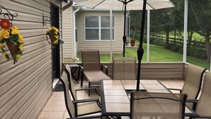 A covered patio with a table and chairs, a potted plant, and a view of the backyard. - Beautiful 3 bed / 2 bath home near Lake Sumter w/ cart, 2 bikes and wi-fi!   (The Villages)