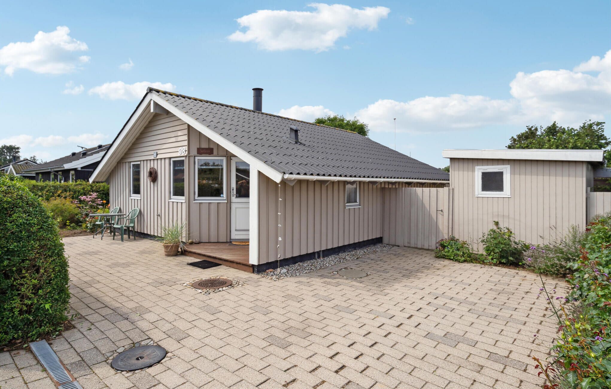 Ein eingeschossiges Haus mit Schrägdach, einer Veranda und einer kleinen angebauten Garage.