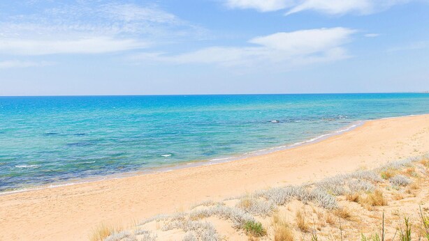 Een strand met helder turquoise water en een zandstrand.