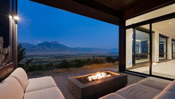 Zona relax esterna moderna con un elemento decorativo a forma di fuoco, con vista su un paesaggio montuoso.