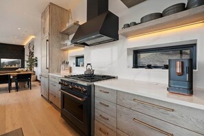 A modern kitchen with a central island, built-in oven, and a large window.