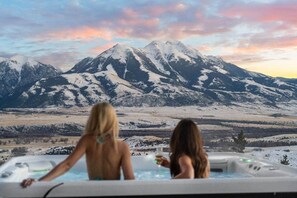Deux personnes dans un jacuzzi, avec un paysage montagneux en arrière-plan.