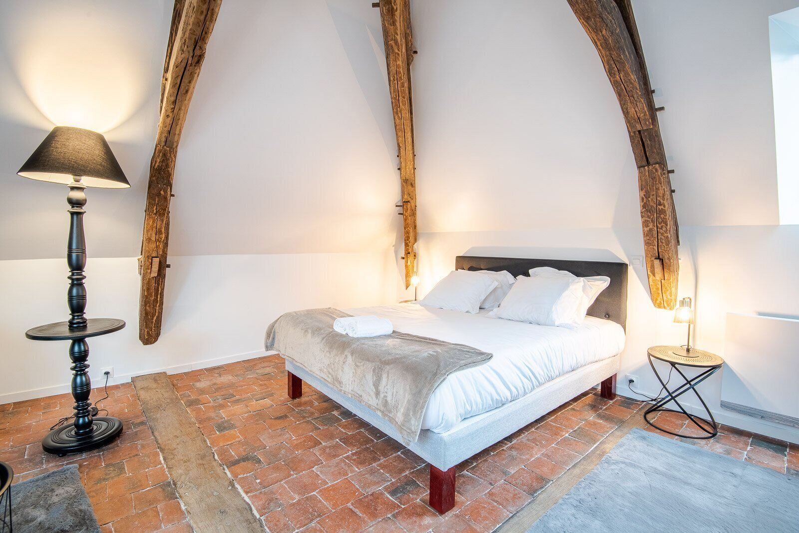 Une chambre à coucher avec un grand lit, une table ronde et une lampe.