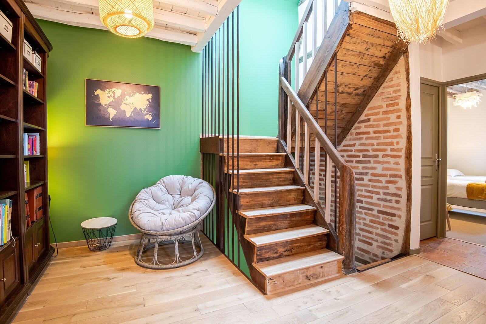 Eine Treppe mit Holzboden und Backsteinwand, die zu einem Zimmer mit einem Bett führt.