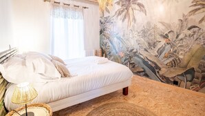 A bedroom with a bed, a woven lamp, a tropical mural, and a wooden ceiling. - Maison paradisiaque avec piscine (Mosnes)