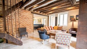 A spacious living area with a brick wall, a staircase, a sofa set, and a coffee table. - Maison paradisiaque avec piscine (Mosnes)