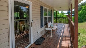 Eine überdachte Veranda mit Holzterrasse, einer Schiebetür und zwei Stühlen.