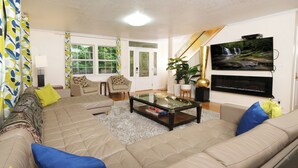 A living room with a beige sectional sofa, a glass coffee table, and a flat-screen TV mounted on the wall. - Hop, Skip and a Jump: Minutes from the Mountains (Sevierville)