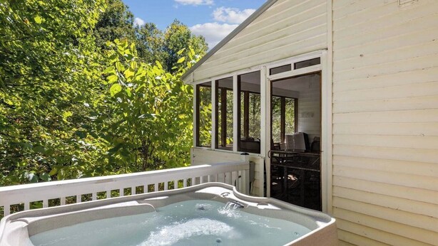 A hot tub on a porch with a view of trees and a covered area with chairs. - Hop, Skip and a Jump: Minutes from the Mountains (Sevierville)