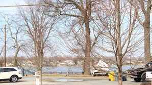 A parking area with trees, a body of water, and a distant view of houses. - Pet Friendly Water View Cottage (Pasadena)