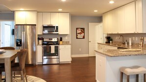 A modern kitchen with stainless steel appliances, white cabinetry, and a granite countertop. - Pet Friendly Water View Cottage (Pasadena)
