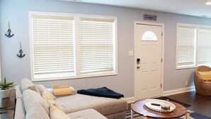 A living room with a sectional sofa, a small round table, and a door with a window. - Pet Friendly Water View Cottage (Pasadena)