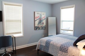 A bedroom with a bed, a chair, a wall-mounted TV, and a poster. - Pet Friendly Water View Cottage (Pasadena)