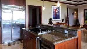 A modern kitchen with a large island, stainless steel appliances, and pendant lighting. - Kolea 10D: 3 Bed/3 Bath Garden Level Condo w Direct Access to Pool & Ocean. (Waikoloa Village)