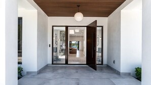A modern interior with a concrete floor, a wooden ceiling, and a large open door leading to a living area with a sofa and a coffee table. - Modern Waterfront Paradise with Heated Pool - Near the Beach & Aventura Mall! (Miami)