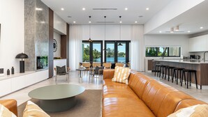 A modern living room with a leather sofa, a coffee table, and a dining area with chairs and a kitchen in the background. - Modern Waterfront Paradise with Heated Pool - Near the Beach & Aventura Mall! (Miami)