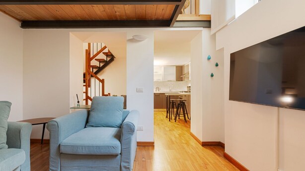 A modern living room with a sofa, a staircase, and a kitchen in the background. - GuestHost - Cozy apartment in St. Ambrose! (Milano)