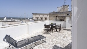Terraço no telhado com mesa e cadeiras, um toldo e vista para a paisagem urbana.